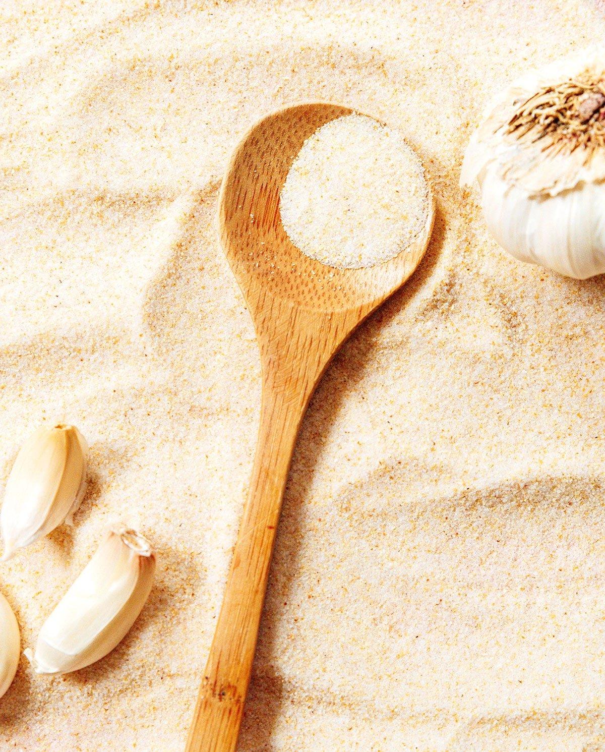 Wie man Knoblauchsalz herstellt 2 Ein Holzlöffel gefüllt mit Knoblauchpulver