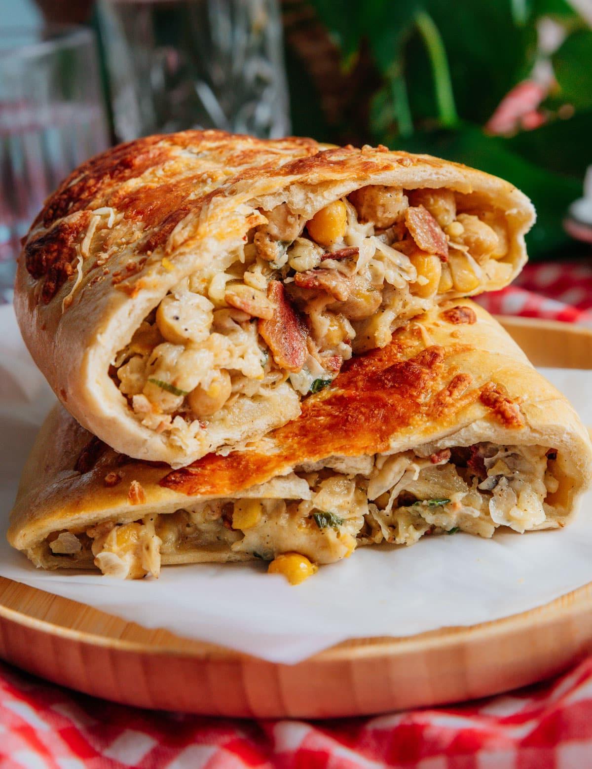 Vegetarischer Costco „Hähnchen“-Auflauf (Mit Kichererbsen!) 2 Auf dem Bild sind vier goldbraune, gefüllte Teigrollen auf Backpapier zu sehen. Sie sind appetitlich angeordnet und mit geschmolzenem Käse bedeckt, was ihre knusprige Textur unterstreicht.
