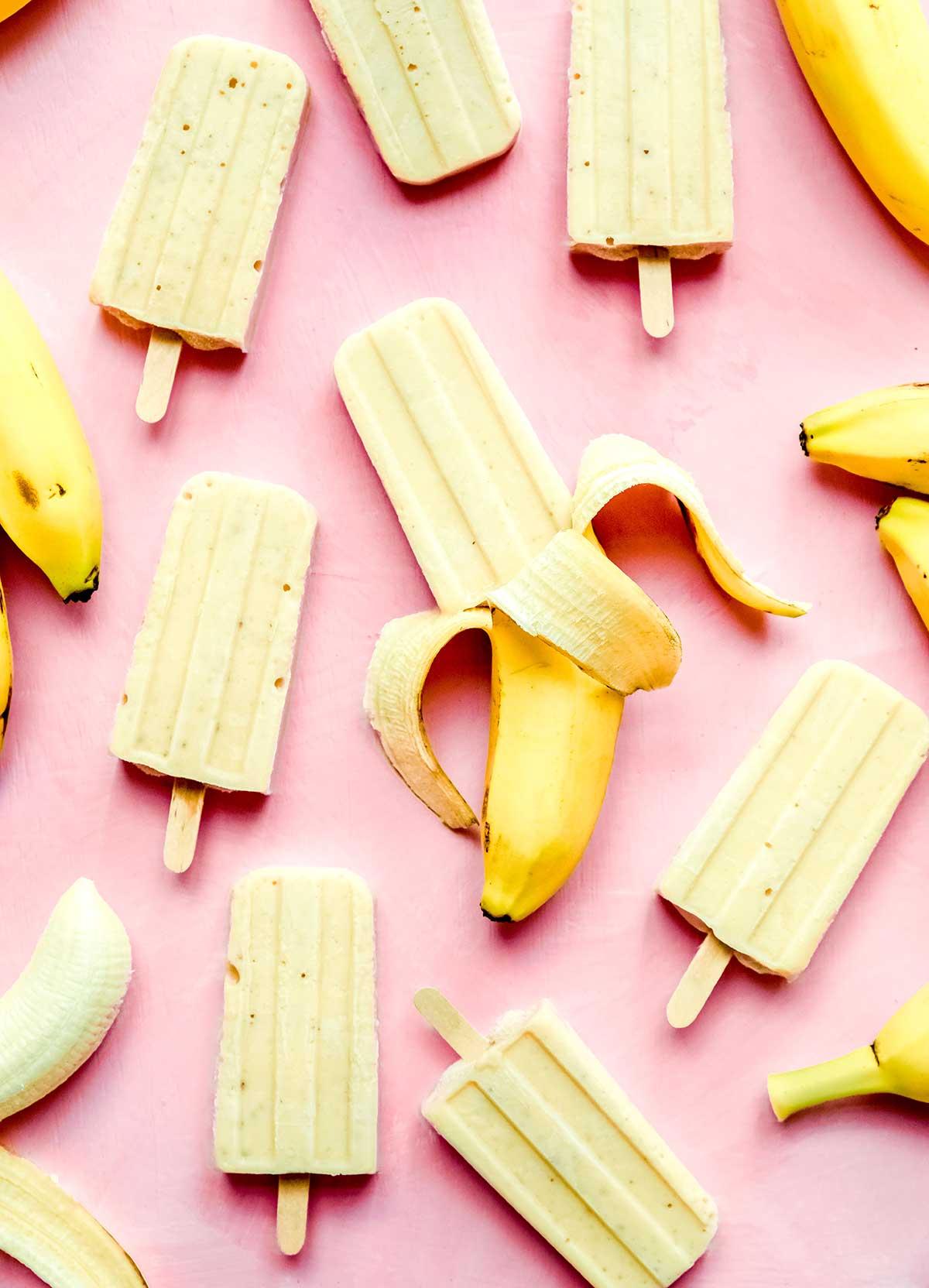 Bananen-Eis am Stiel aus 3 Zutaten 2 Viele Bananen-Popsicles auf einem pinkfarbenen Hintergrund.