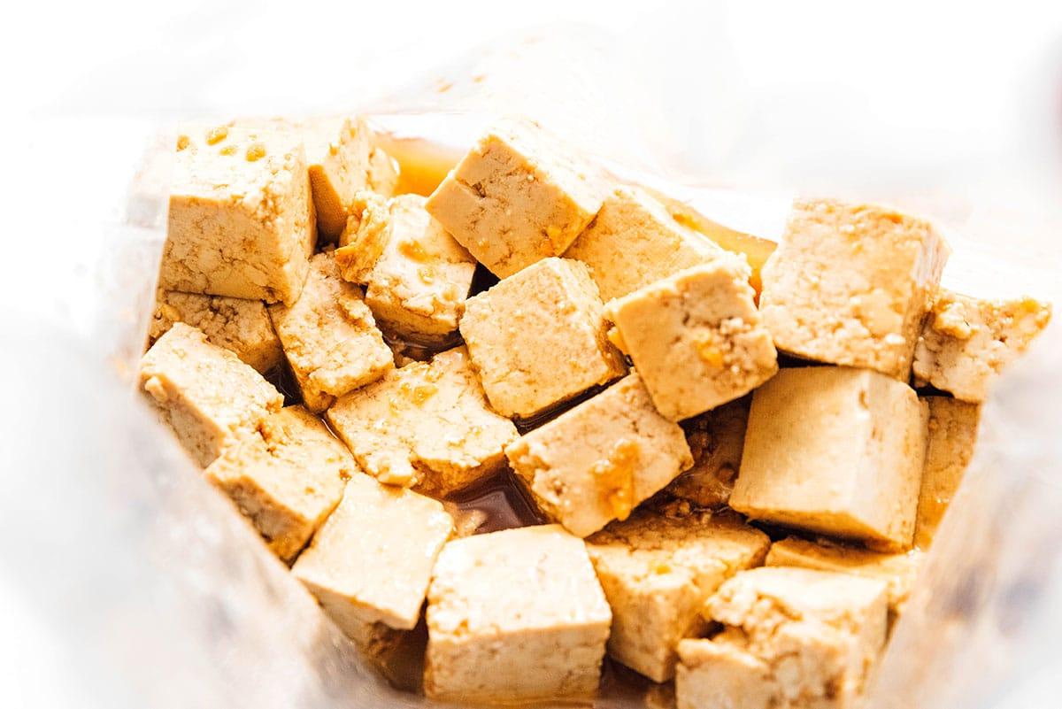 Wie man Tofu mariniert (8 Geschmacksrichtungen!) 11 Tofu-Würfel in einem Beutel voller Sesam-Ingwer-Marinade.