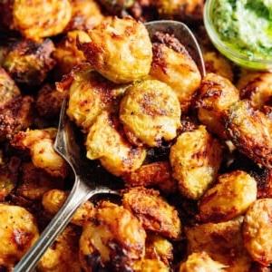 TikTok-viraler knuspriger zerdrückter Rosenkohl 13 Knuspriger zerdrückter Rosenkohl auf einer Platte mit grüner Pesto-Mayo-Sauce.