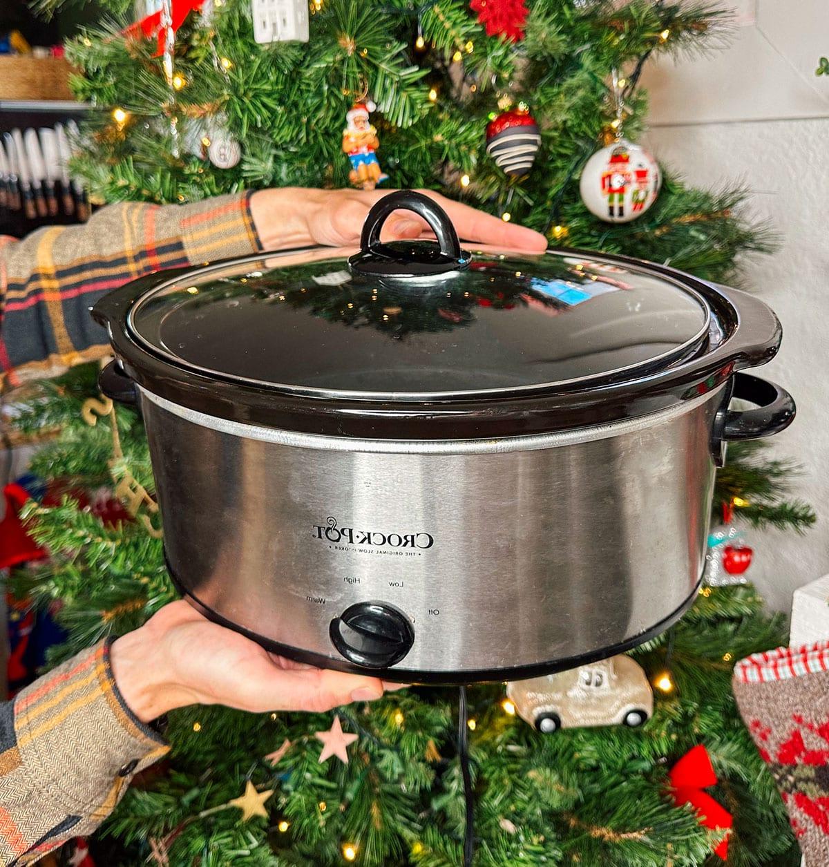 Ein Crock-Pot Slow Cooker als Geschenk vor einem Weihnachtsbaum.
