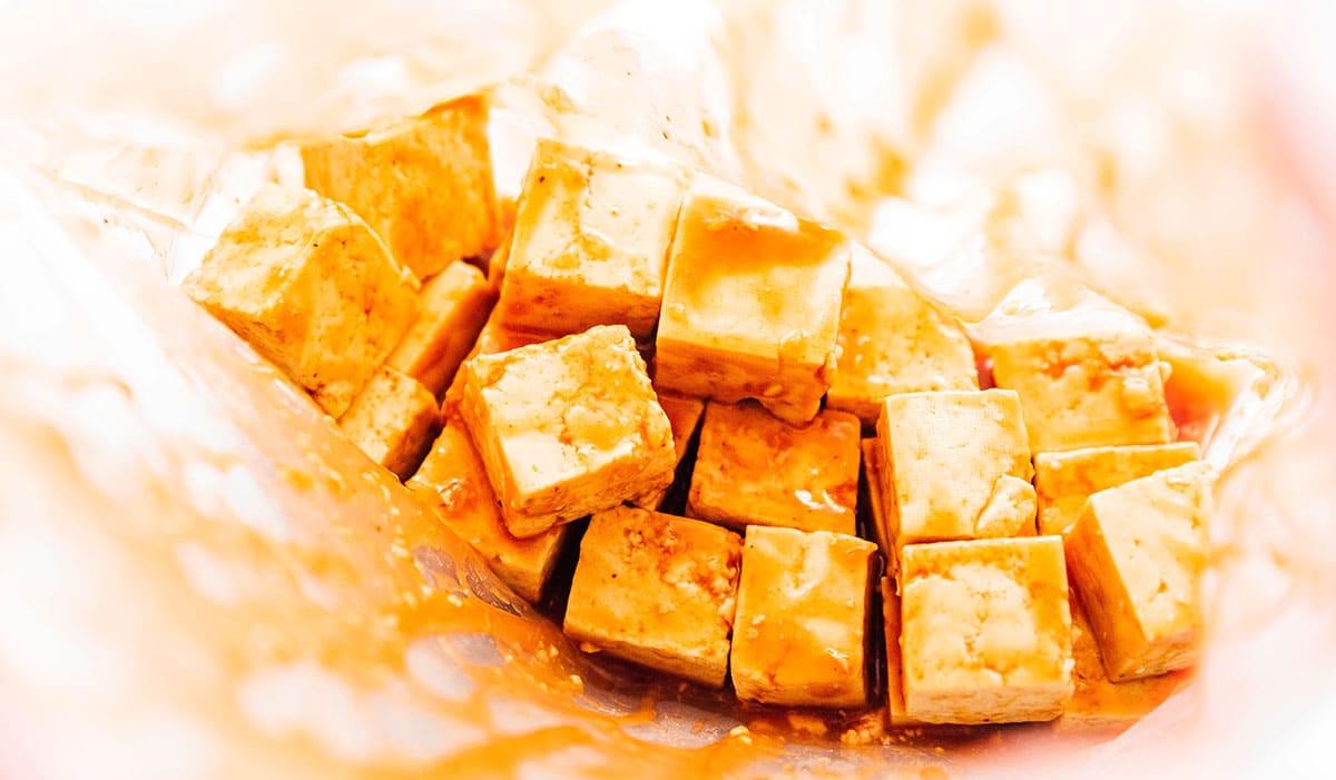 Wie man Tofu mariniert (8 Geschmacksrichtungen!) 14 Tofu-Würfel und Barbecue-Marinade in einem Druckverschlussbeutel.