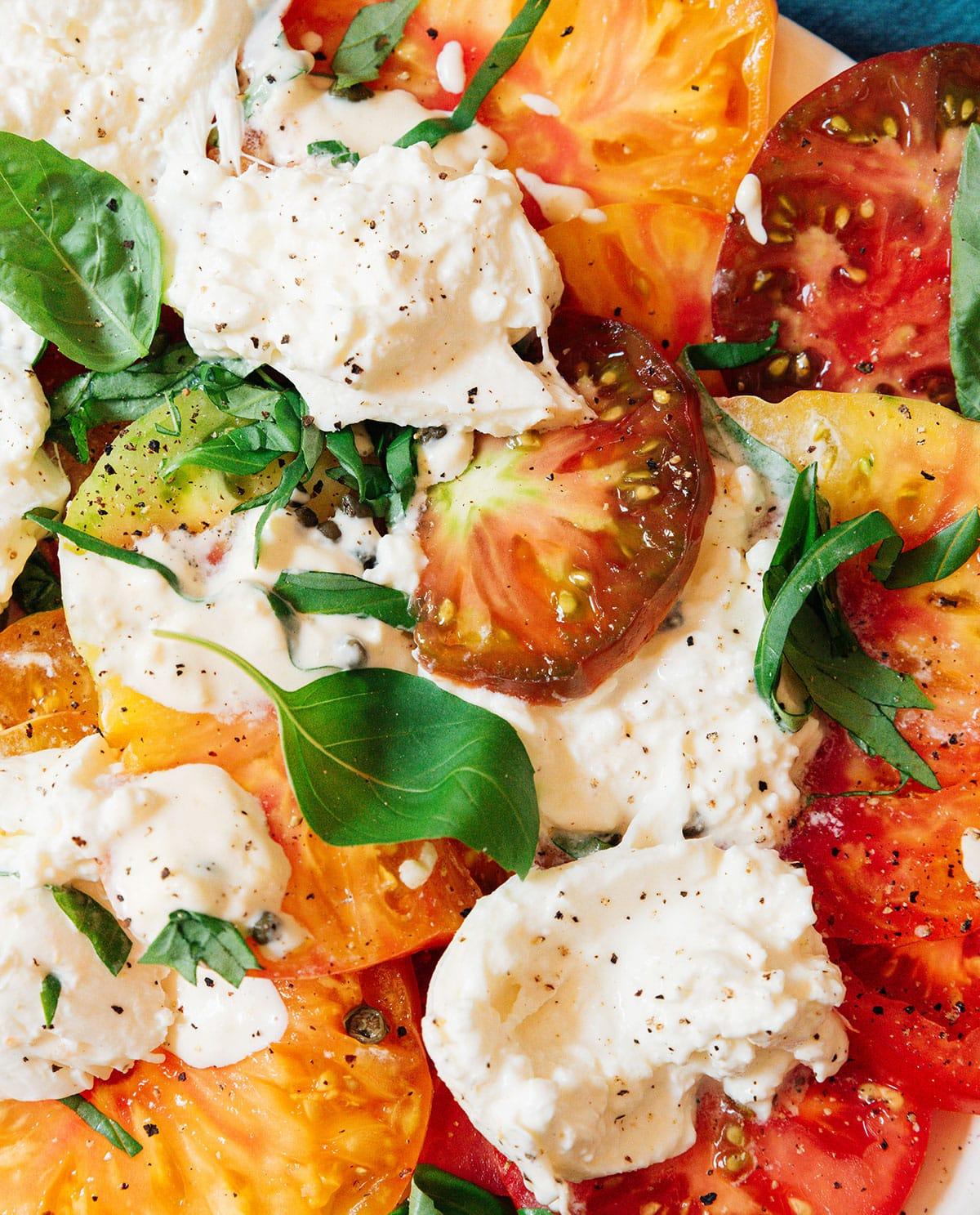 Vegetarische 31-Tage-Herausforderung 14 Tomaten-Burrata-Salat auf einer Platte angerichtet.