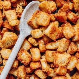 Croutons in einer Pfanne mit einem Löffel.