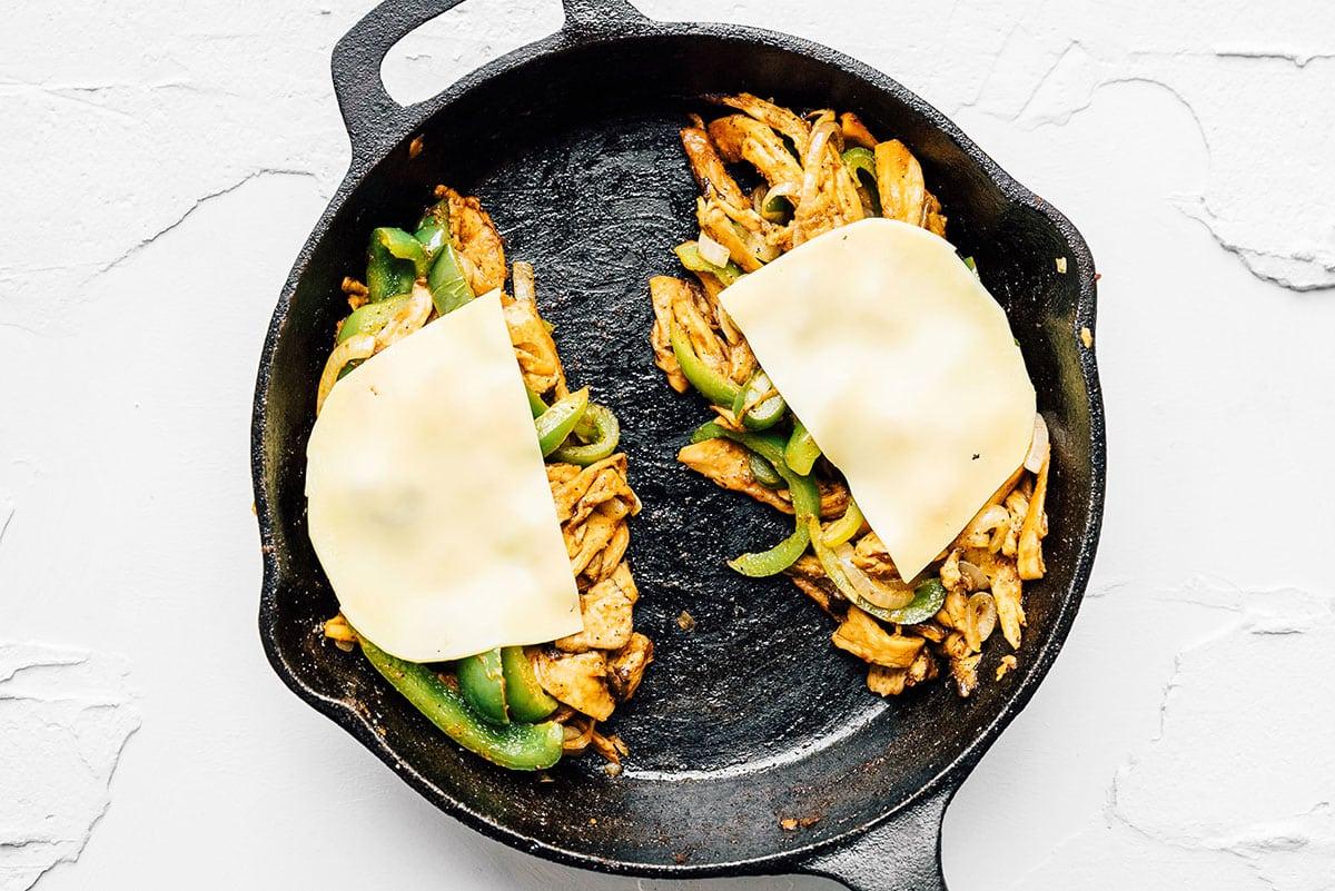 Ein vegetarisches Cheesesteak wird in einer gusseisernen Pfanne zubereitet.