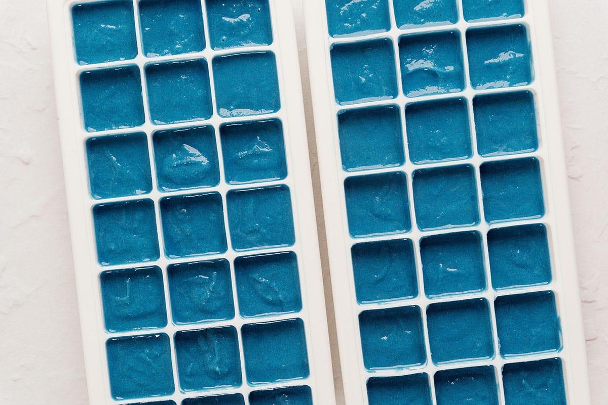 Blaue Smoothie-Würfel werden in Eiswürfelformen gefüllt.