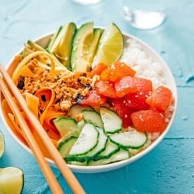 Vegane Tomaten-Thunfisch-Sushi-Bowl mit Reis, Avocado und Gurke in einer Schüssel auf blauem Hintergrund