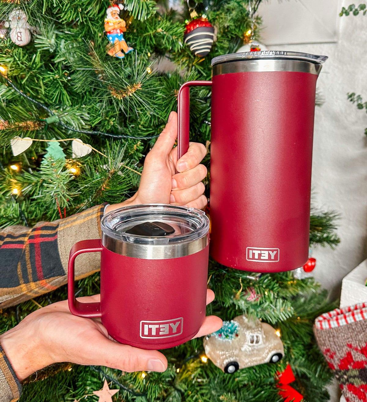 Ein Yeti Rambler Krug mit Bechern als Geschenk vor einem Weihnachtsbaum.