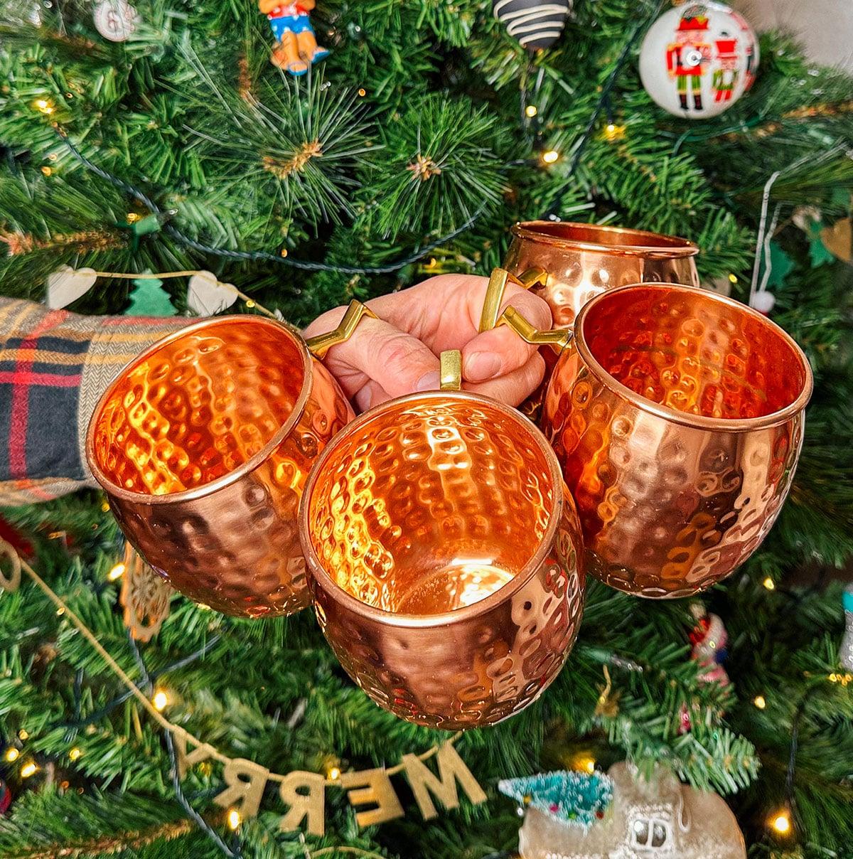 Kupferbecher für Moscow Mule als Geschenk vor einem Weihnachtsbaum.