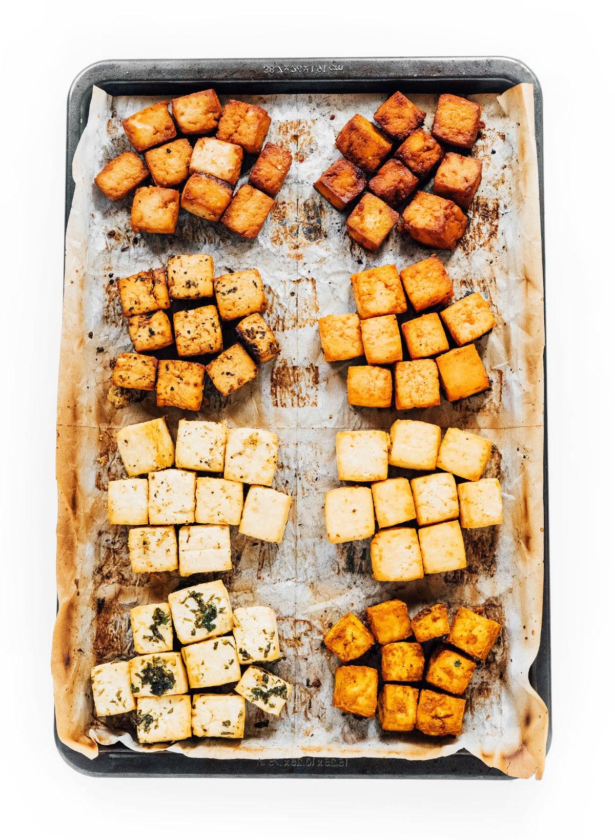 Wie man Tofu mariniert (8 Geschmacksrichtungen!) 3 Ein mit Backpapier ausgelegtes Backblech mit 8 verschiedenen Sorten marinierter Tofu-Würfel.