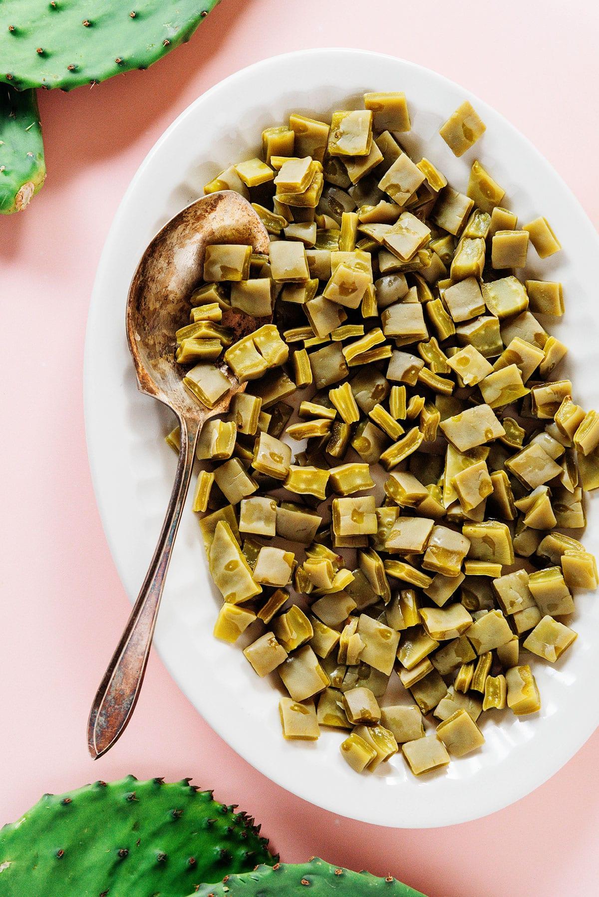 Nopales zubereiten (Kaktusblätter!) 3 Gewürfelte, gekochte Nopales auf einer weißen Platte mit einem Servierlöffel