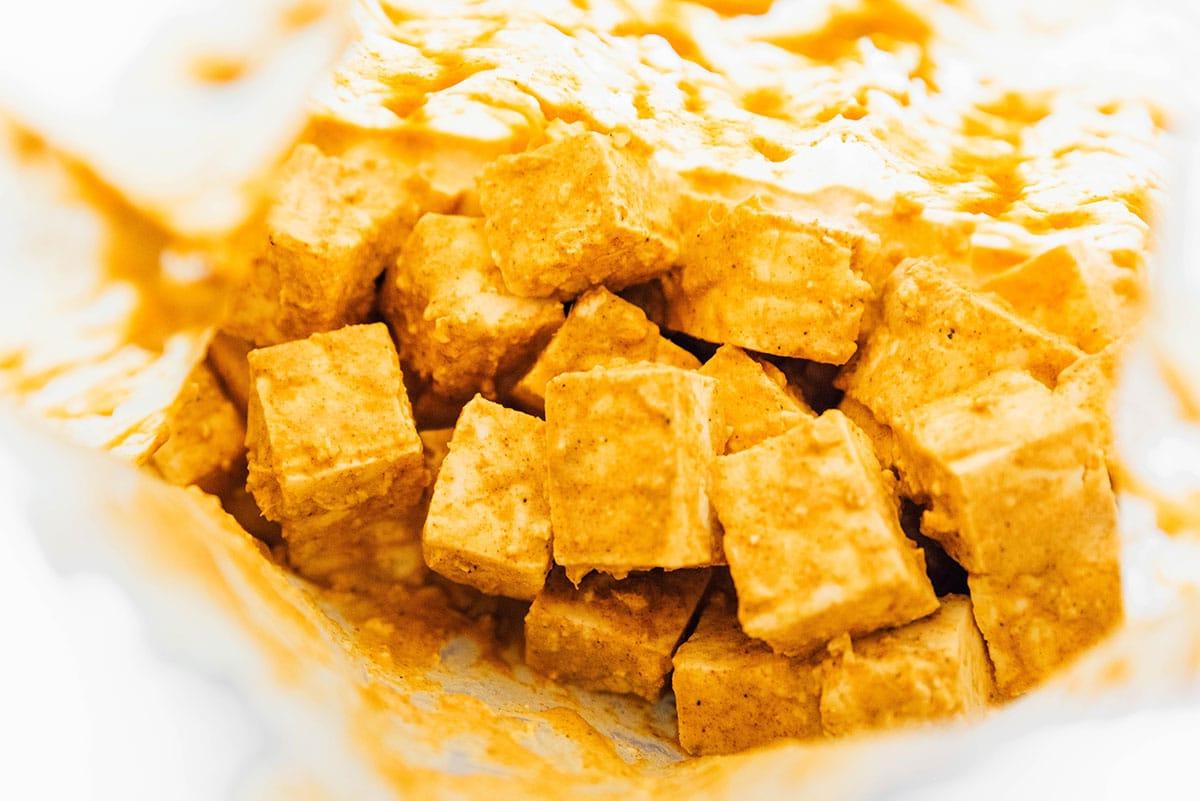 Wie man Tofu mariniert (8 Geschmacksrichtungen!) 26 Tandoori-gewürzte Tofu-Würfel in einem Beutel.