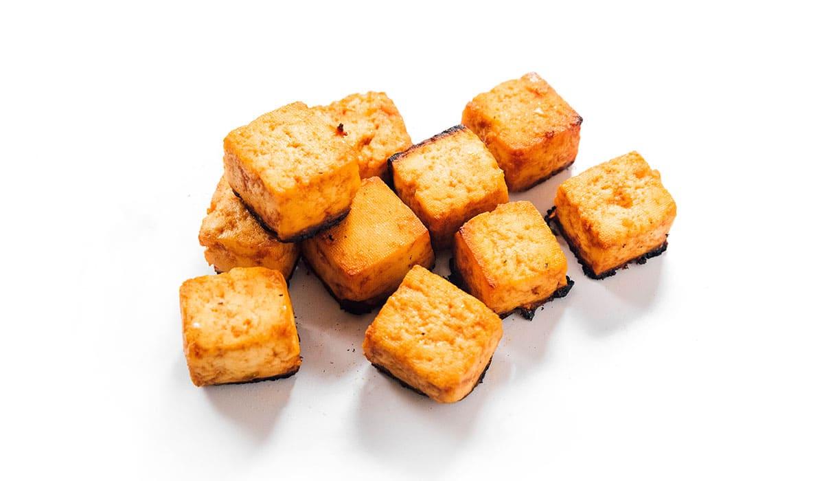 Wie man Tofu mariniert (8 Geschmacksrichtungen!) 27 Gebackene Tandoori-Tofu-Würfel auf einer weißen Oberfläche.