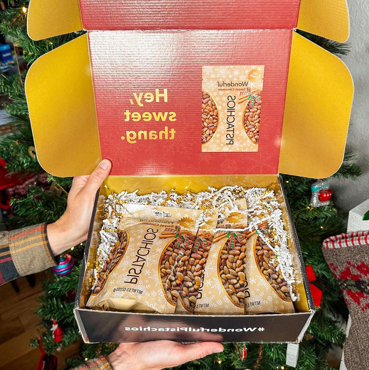 Wonderful Pistazien mit Zimtgeschmack als Geschenk vor einem Weihnachtsbaum.