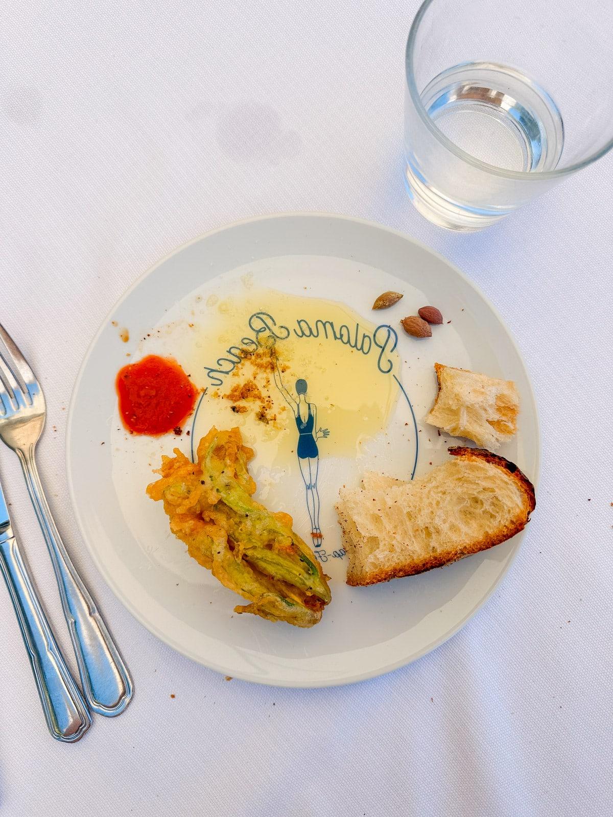 Ein Feinschmecker in Frankreich 28 Focaccia und Burrata-Tomaten-Salat auf einem Teller, am Strand mit Meerblick.