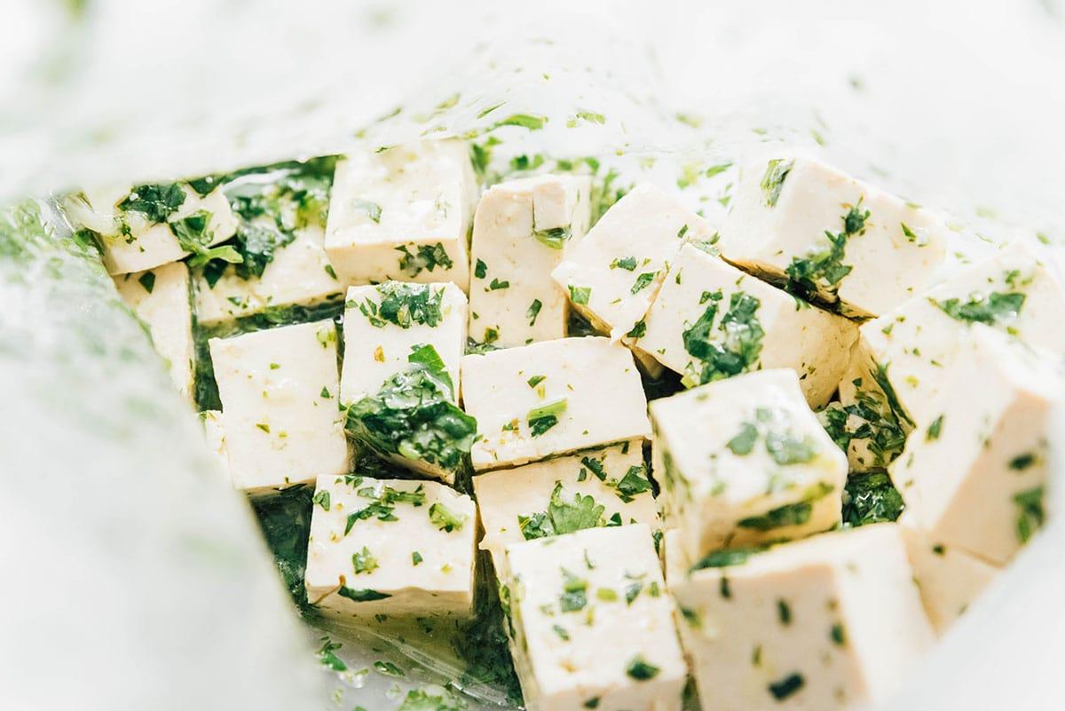 Wie man Tofu mariniert (8 Geschmacksrichtungen!) 29 Koriander-Limetten-Marinade und Tofu-Würfel in einem Druckverschlussbeutel kombiniert.