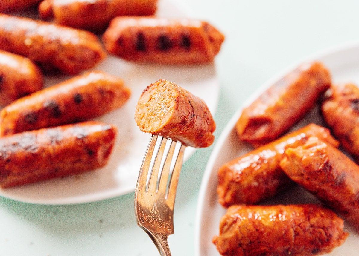 Vegetarische Cevapcici (Kroatisches Cevapi-Sandwich-Rezept) 4 Vegane Wurst auf einer Gabel.
