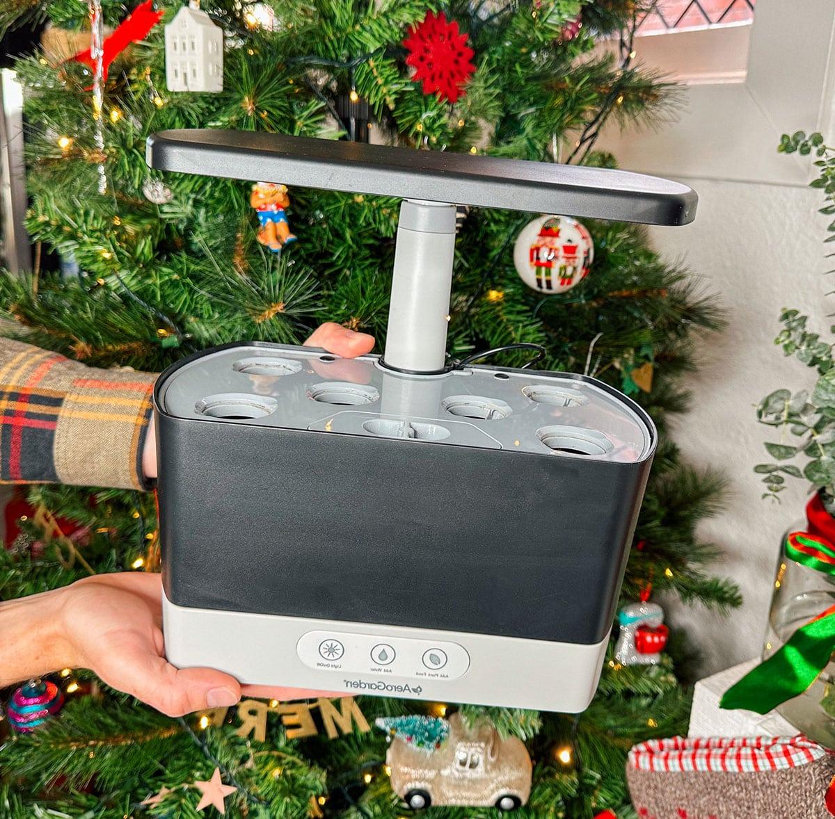 Ein AeroGarden Hydroponik-Garten als Geschenk vor einem Weihnachtsbaum.
