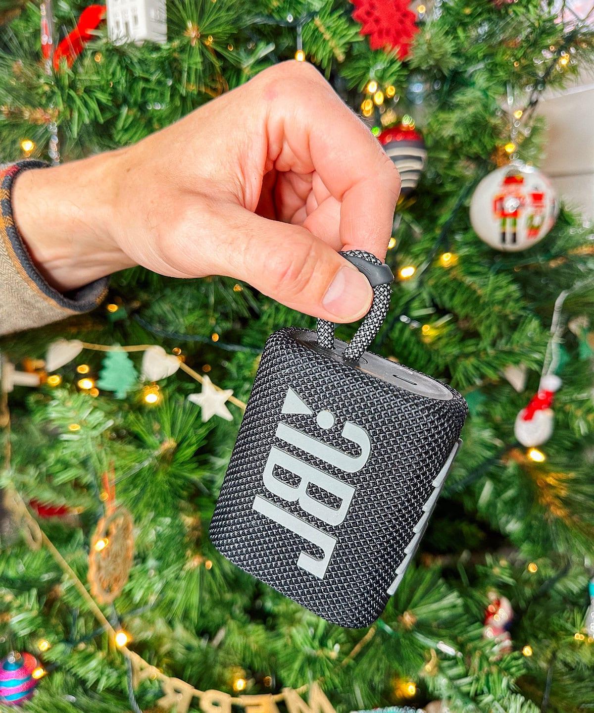 Ein JBL Mini Lautsprecher als Geschenk vor einem Weihnachtsbaum.