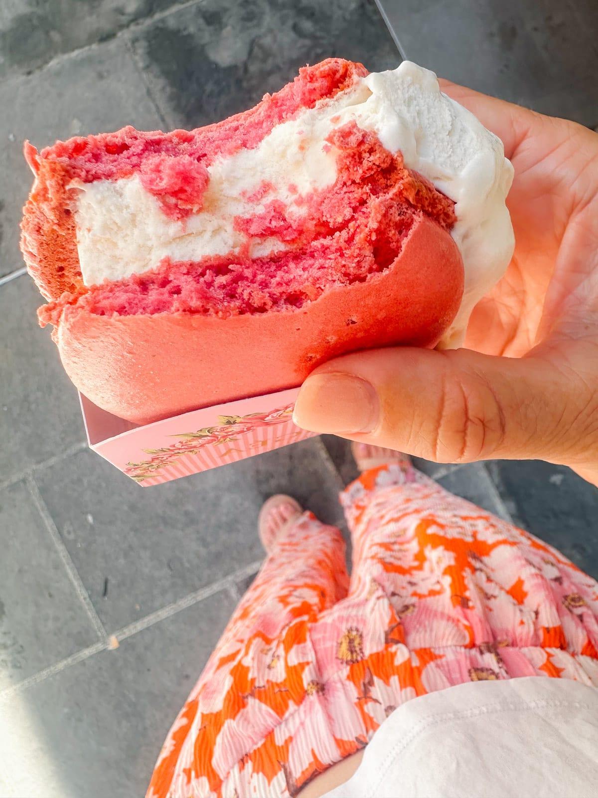 Ein Feinschmecker in Frankreich 38 Hand hält ein riesiges Macaron-Eis-Sandwich, das aussieht wie ein Regenbogen.