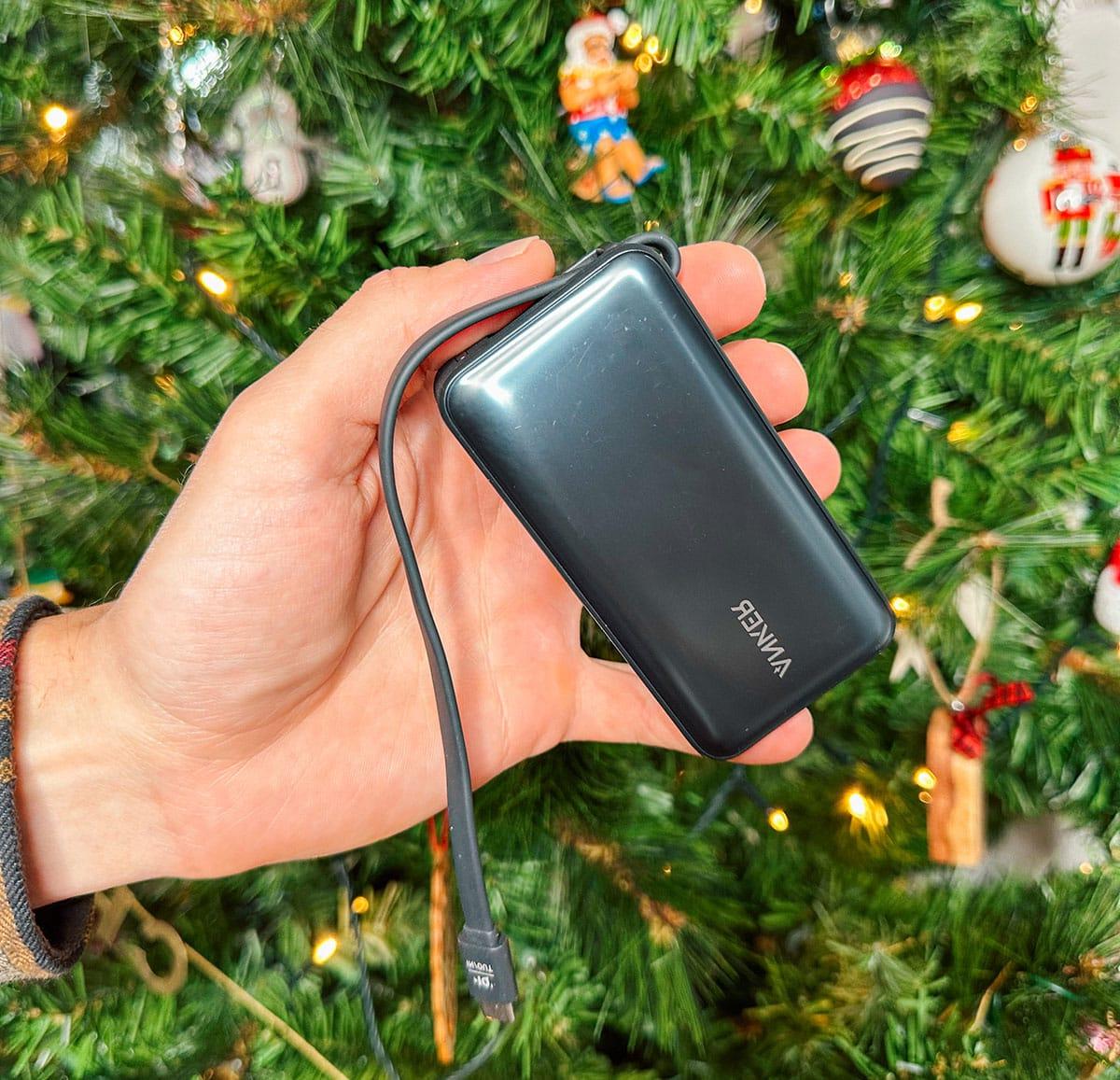 Ein tragbares Ladegerät von Anker als Geschenk vor einem Weihnachtsbaum.