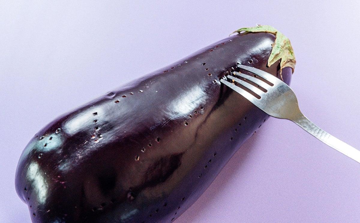Griechischer Auberginen-Dip (Melitzanosalata) 5 Eine Gabel, die Löcher in eine Aubergine sticht.
