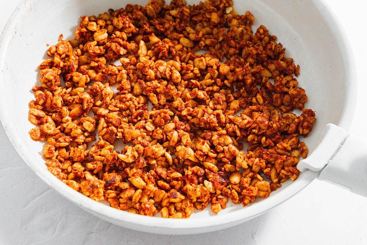 Tempeh Taco Fleisch 5 Veganes Tempeh-Taco-Fleisch wird in einer Sauteuse auf weißem Hintergrund angebraten und gewürzt.