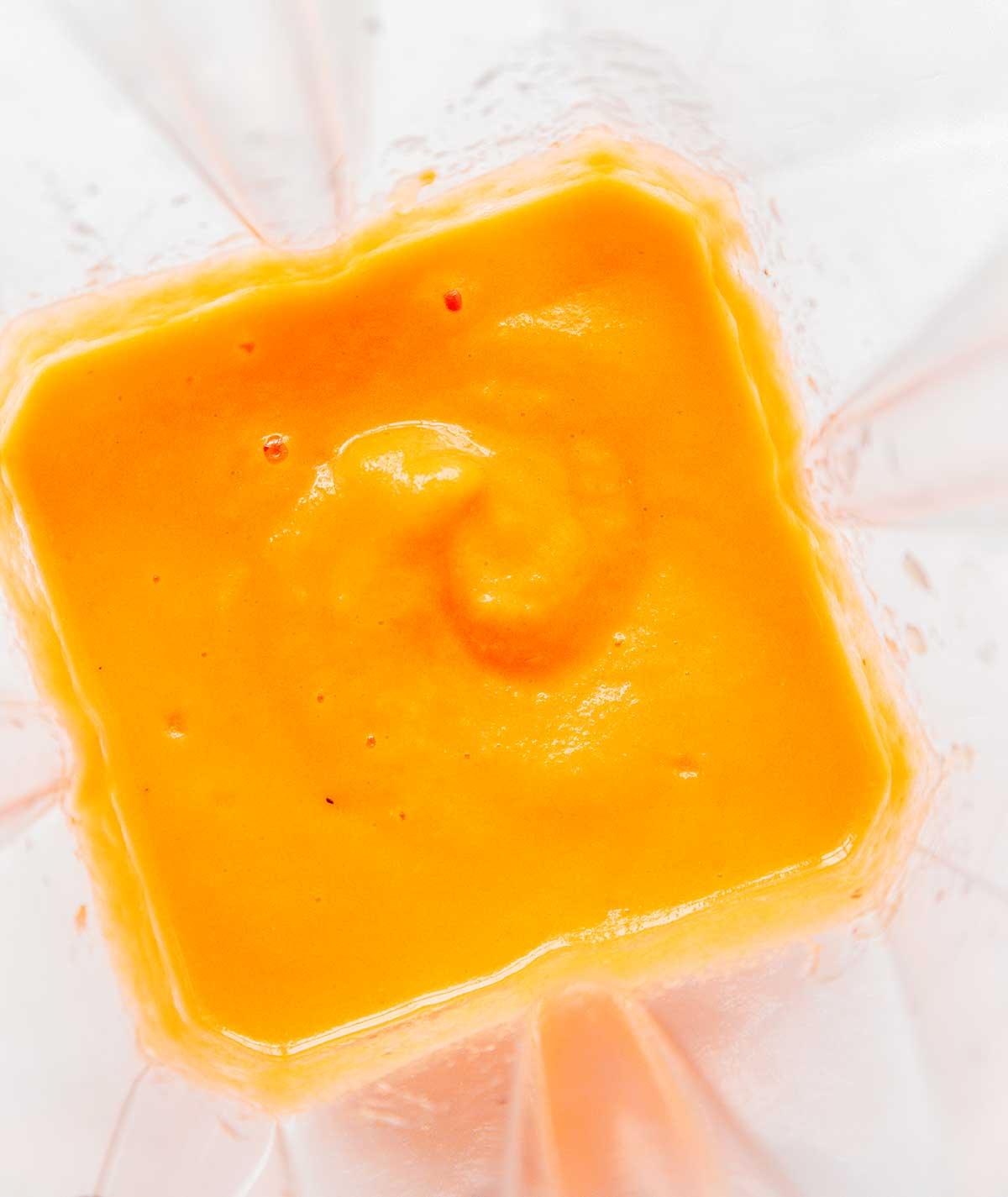 Ein Mixer gefüllt mit frisch gemischtem Karotten-Smoothie mit Zitrusfrüchten und Ingwer