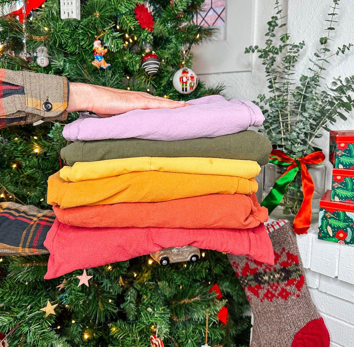 Bunte Overalls als stylisches Geschenk vor einem Weihnachtsbaum.