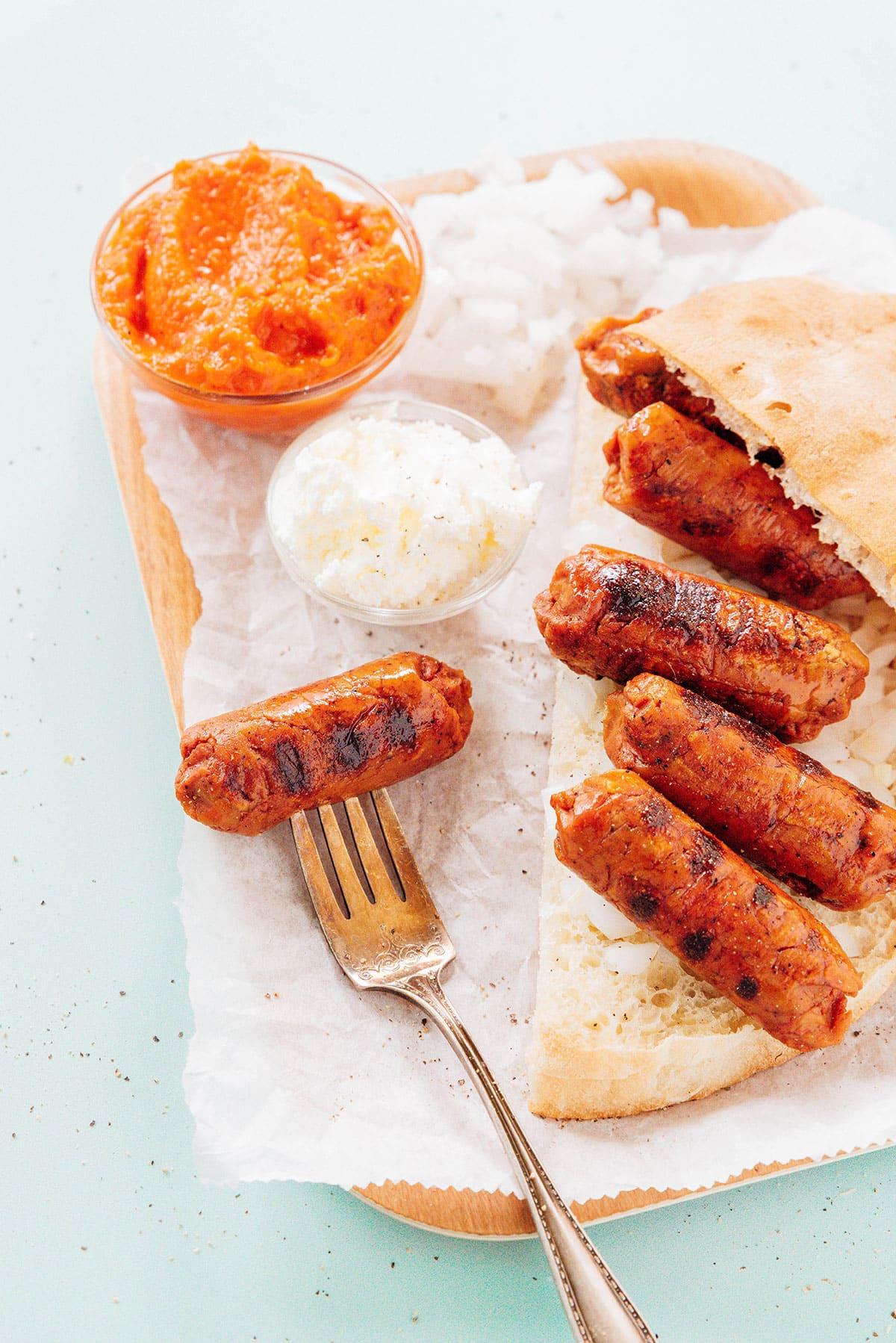 Vegetarische Cevapcici (Kroatisches Cevapi-Sandwich-Rezept) 6 Vegetarische Cevapi auf einem Teller mit Ajvar und Kajmak.