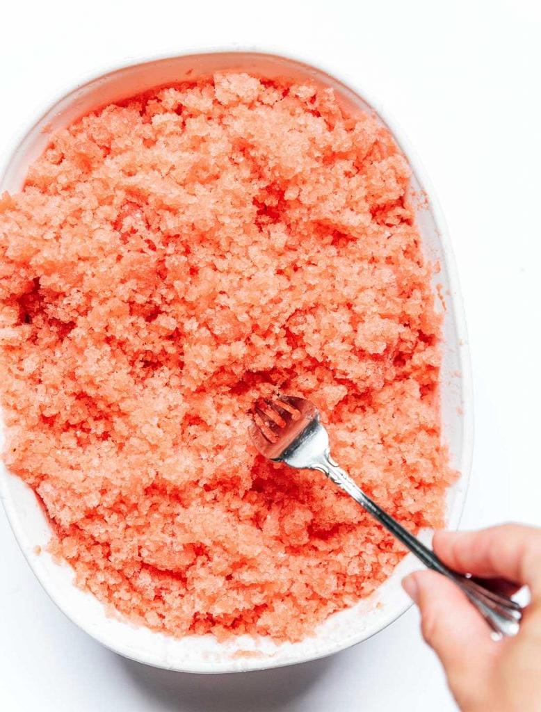 Einfache Wassermelonen-Granita 6 Wassermelonen-Granita mit einer Gabel in einer weißen Schale schaben, um Eiskristalle zu bilden