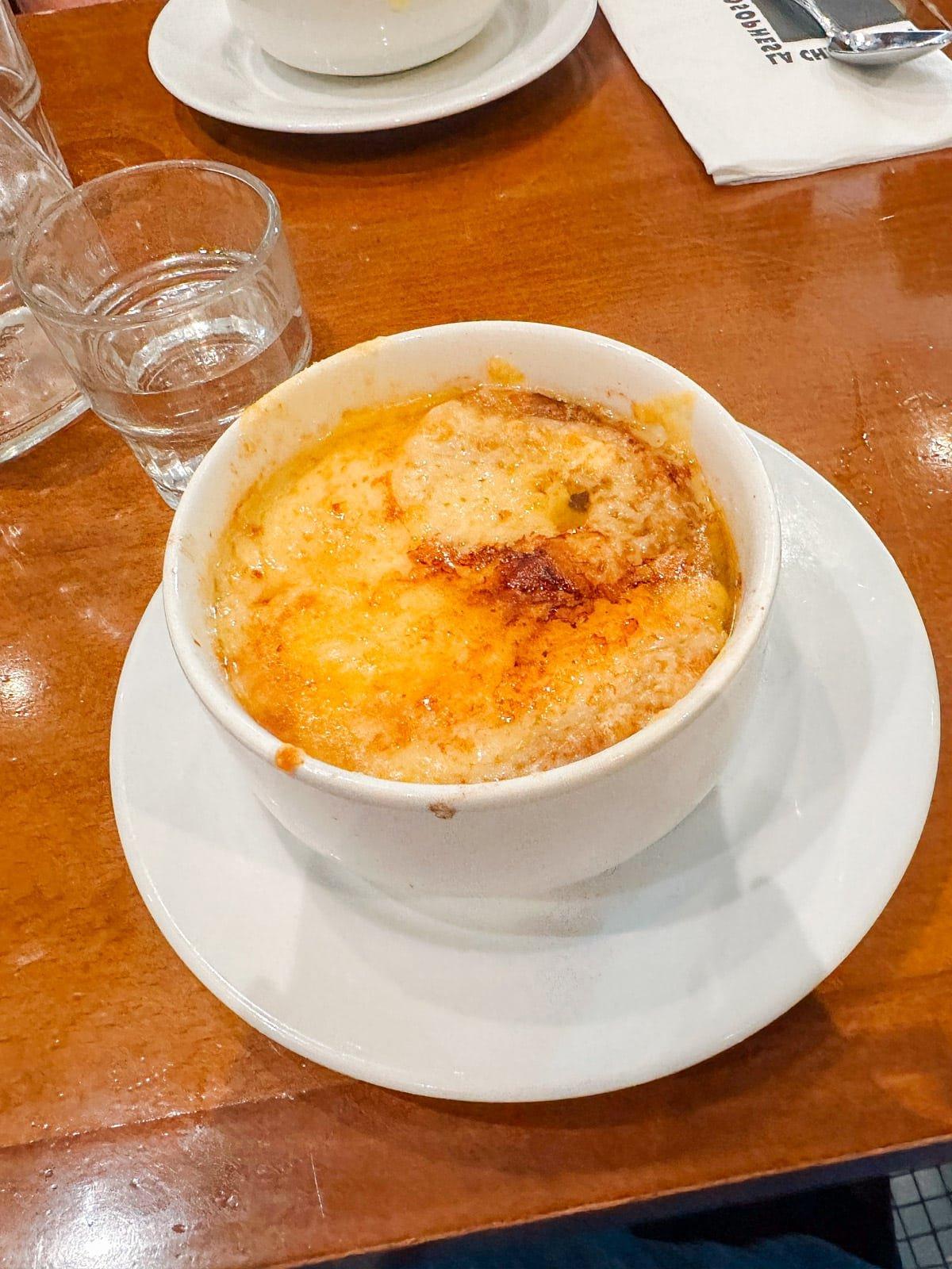 Ein Feinschmecker in Frankreich 6 Eine dampfende Schale französischer Zwiebelsuppe, reichlich mit geschmolzenem Käse bedeckt.