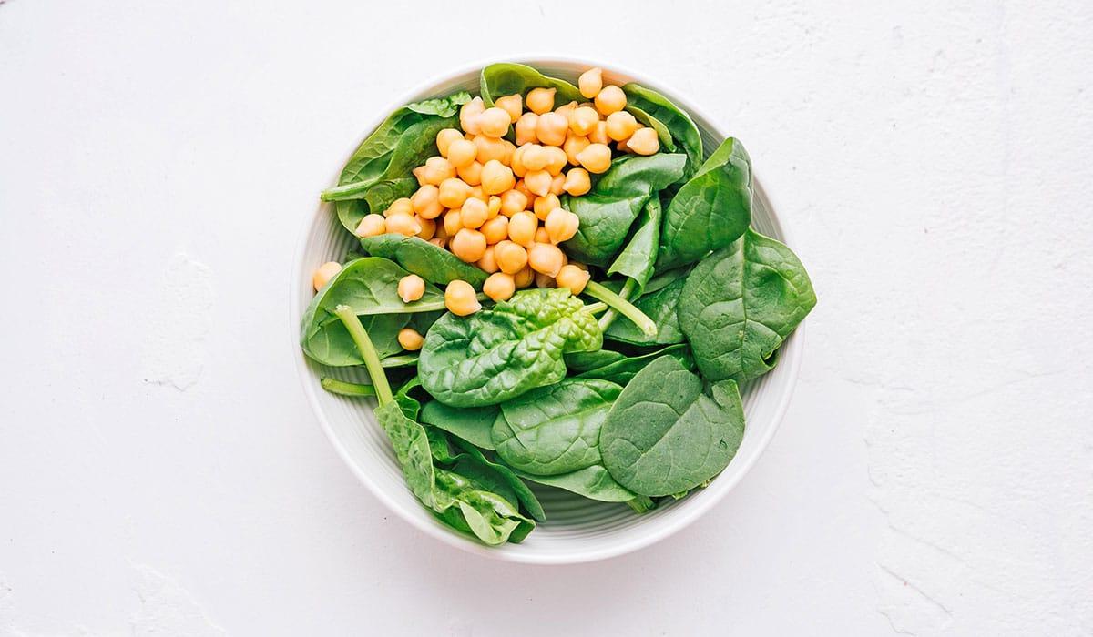 **Wie man eine Buddha Bowl zusammenstellt** 6 Kichererbsen und Spinat in einer weißen Schüssel