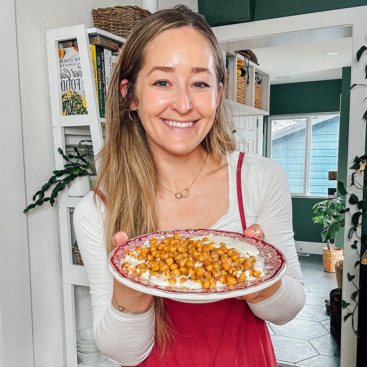 Geröstete Kichererbsen mit Chili-Honig und Aufgeschlagenem Feta 6 Sarah hält einen Teller mit Hot Honey gerösteten Kichererbsen.