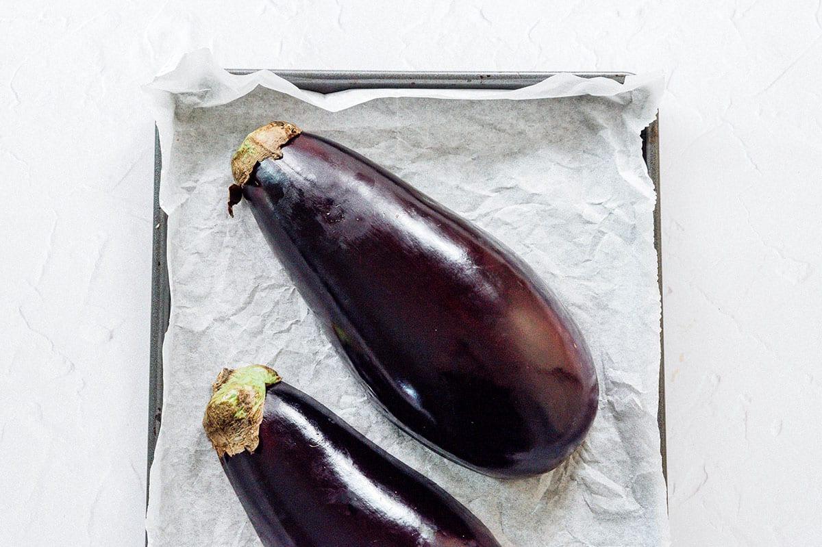 Geröstete Aubergine mit Feta-Minz-Soße 6 Halbierte Aubergine mit der Schnittfläche nach unten auf einem Backblech liegend.