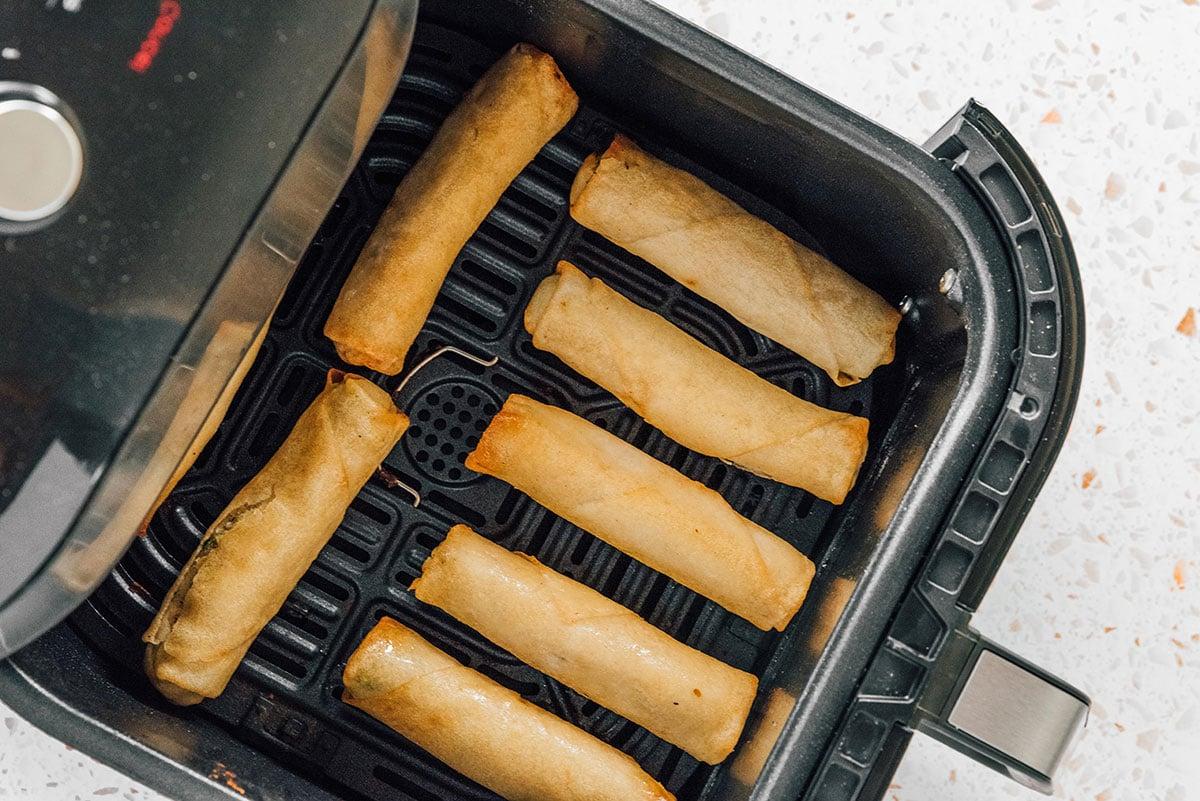 Die knusprigsten tiefgekühlten Frühlingsrollen aus der Heißluftfritteuse 7 Frühlingsrollen in einem Heißluftfritteusenkorb mit Abstand zueinander angeordnet.