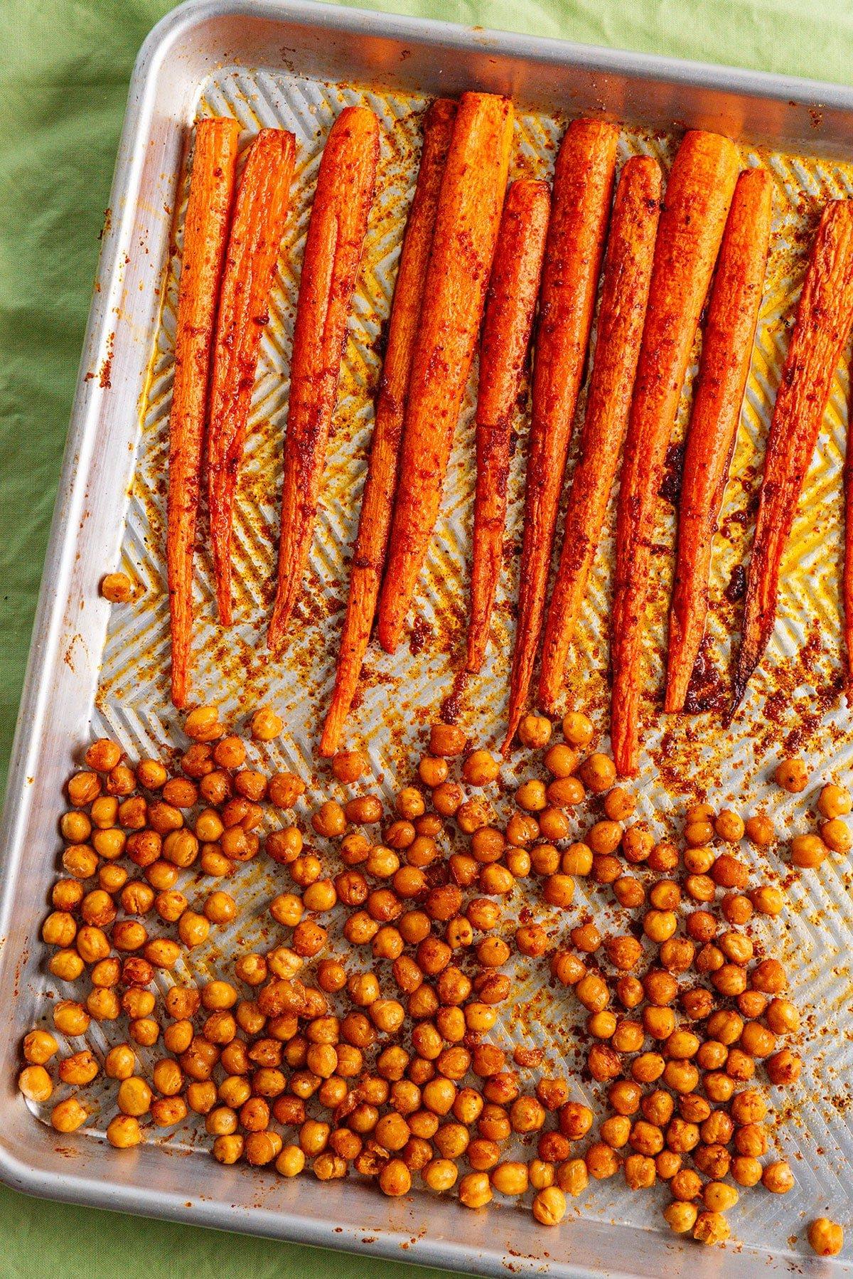 Geröstete Karotten mit knusprigen Kichererbsen 7 Karotten und Kichererbsen auf einem Backblech nach dem Rösten, goldbraun und knusprig.