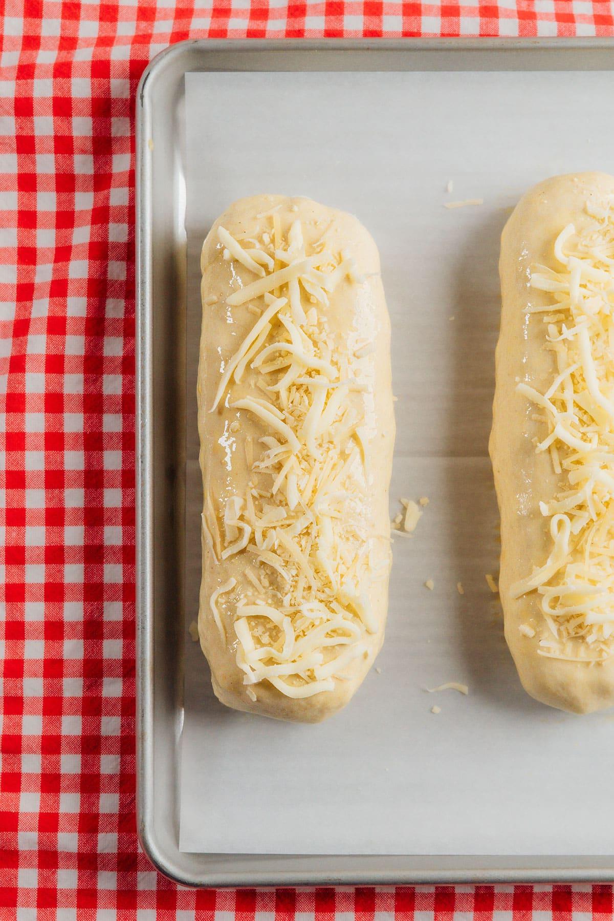 Vegetarischer Costco „Hähnchen“-Auflauf (Mit Kichererbsen!) 7 Eine Nahaufnahme zeigt eine Füllung aus Kichererbsen, Käse und Kräutern, die auf einem Teigbett liegt, welches bereit ist, zu einem 'Bake' geformt zu werden. Der Hintergrund ist leicht unscharf und kariert, was eine gemütliche Küchenatmosphäre schafft.