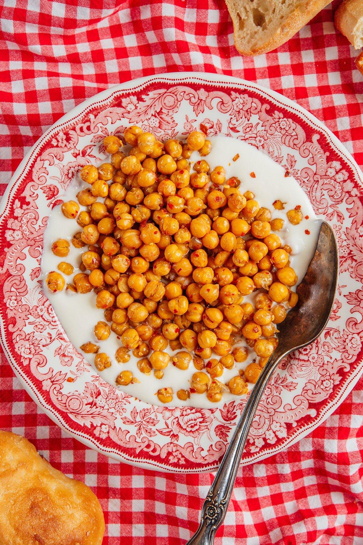 Geröstete Kichererbsen mit Chili-Honig und Aufgeschlagenem Feta 7 Hot Honey Kichererbsen mit cremigem Feta-Dip auf einer Servierplatte.