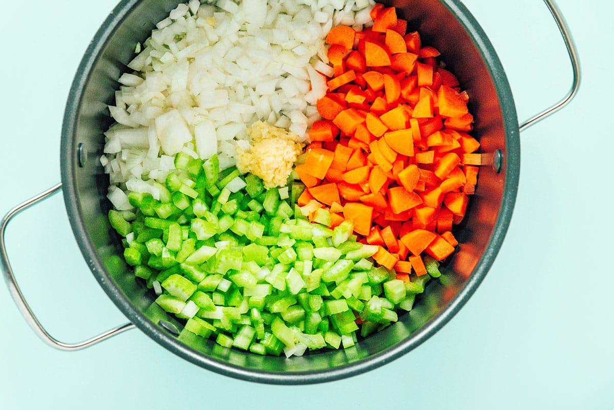 Cremige Vegane Wildreissuppe 7 Sellerie, Karotten und Zwiebeln in einem Topf.