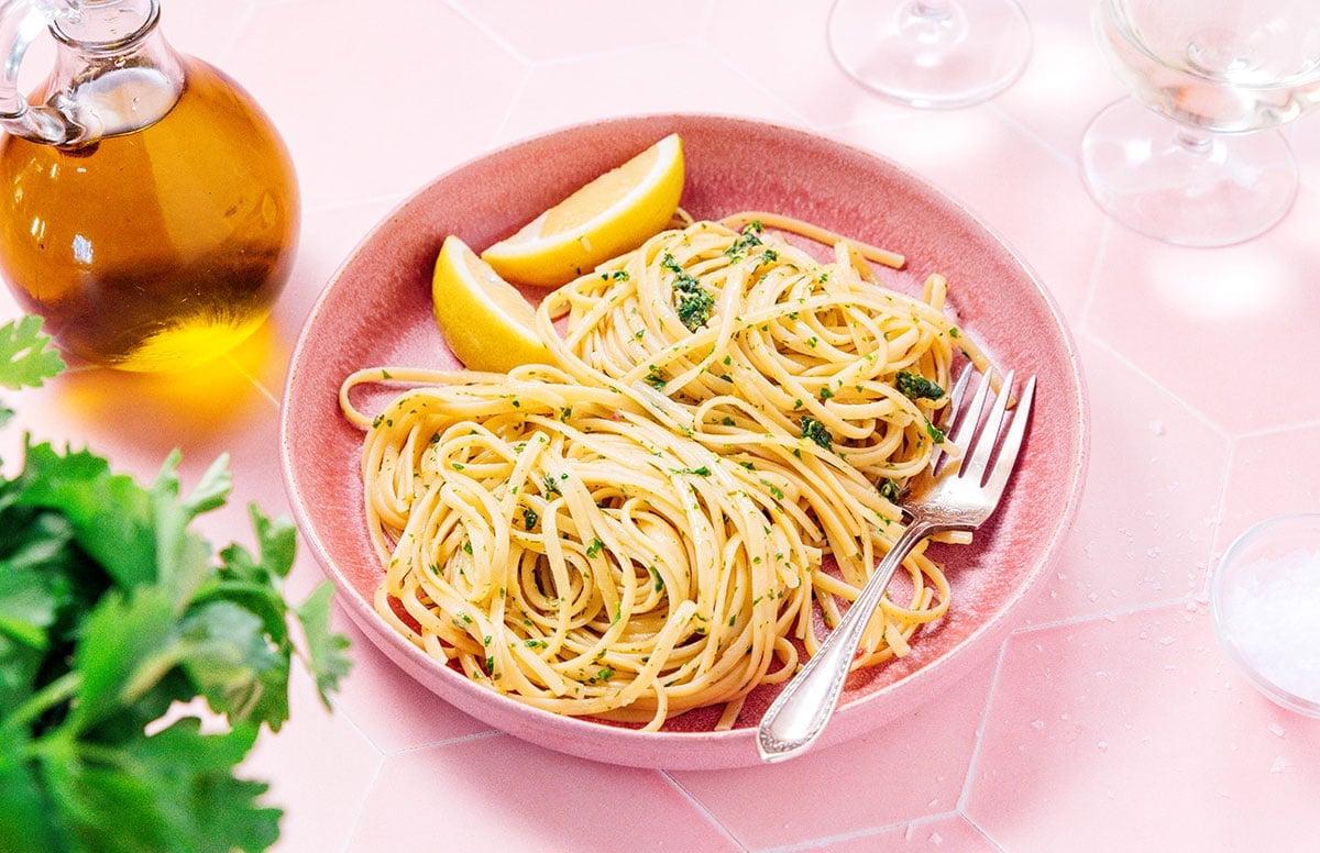 Zitronige Gremolata Pasta (Fertig in 15 Minuten) 7 Eine rosa Schüssel gefüllt mit Gremolata Pasta und zwei Zitronenspalten