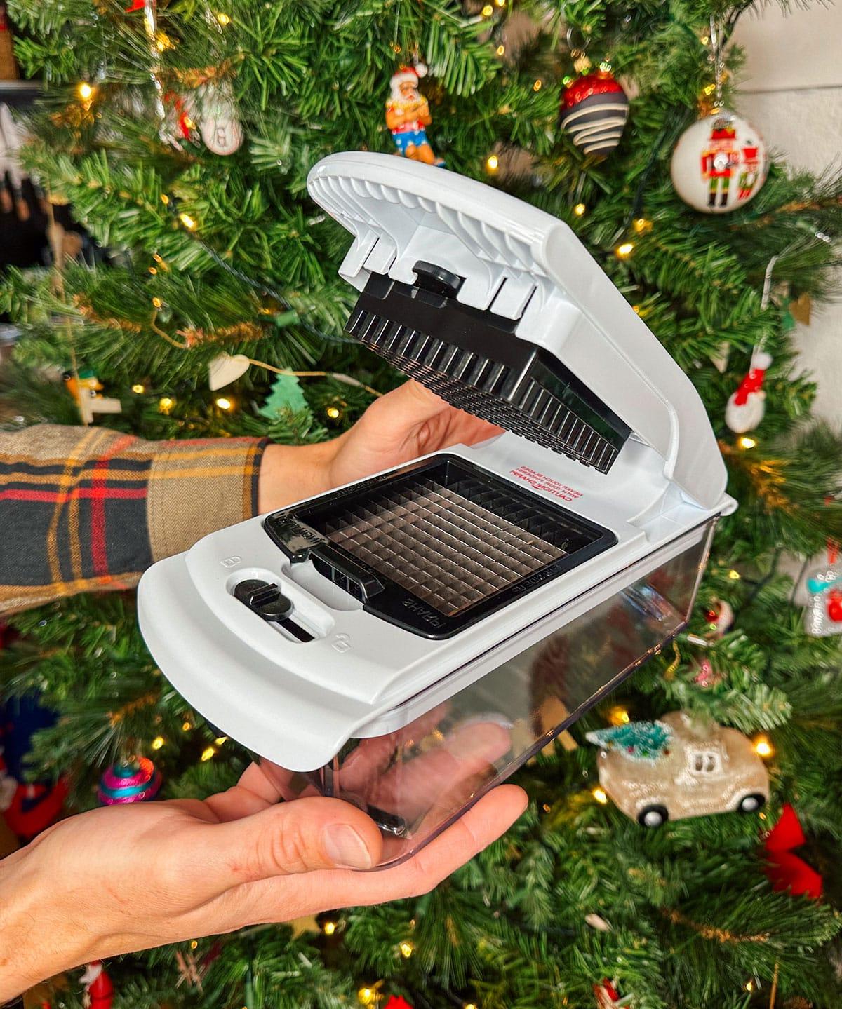 Ein praktischer Gemüseschneider als Geschenk vor einem Weihnachtsbaum.