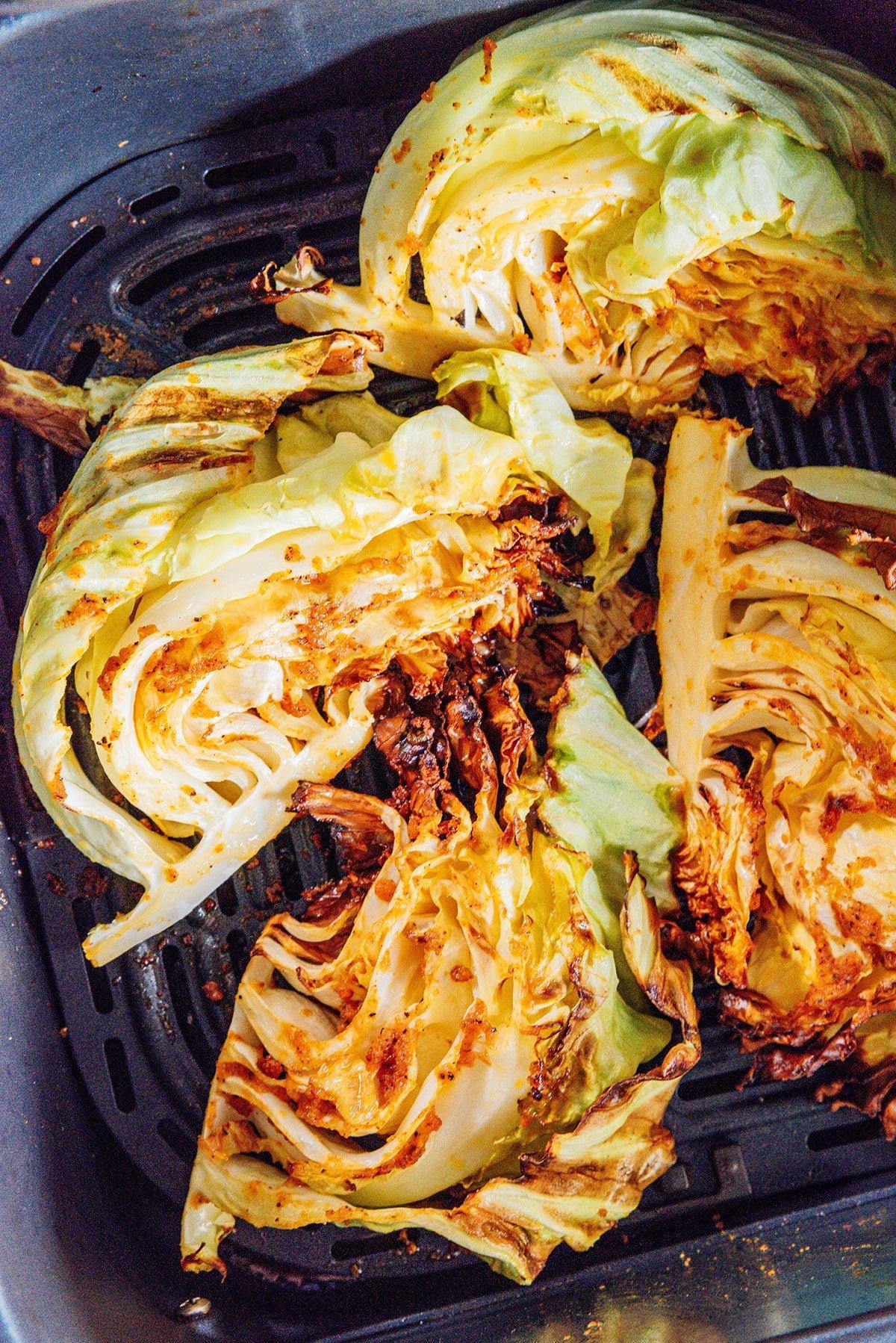 Einfacher Heißluftfritteusen-Kohl 7 Fertige Kohlspalten aus der Heißluftfritteuse in einem Airfryer-Korb.