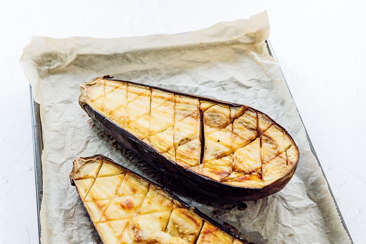 Geröstete Aubergine mit Feta-Minz-Soße 7 Nach dem Backen aufgeschnittene Aubergine auf einem Blech.