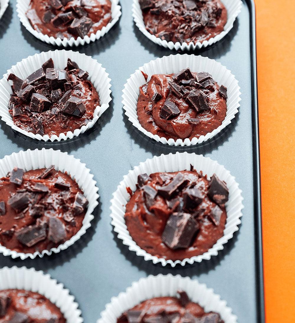 12 Ersatzstoffe für Kakaopulver (und wie man sie verwendet) 8 Gesunde Schokoladenmuffins in einer Muffinform auf orangefarbenem Hintergrund.