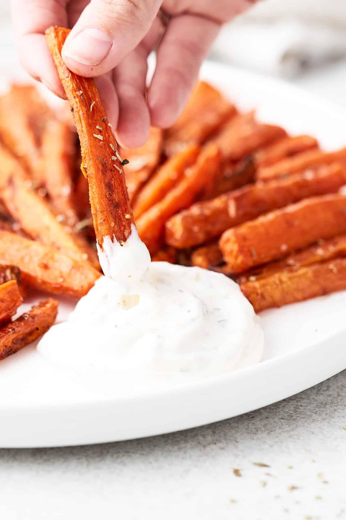 Knusprige Karotten-Pommes aus der Heißluftfritteuse 8 Ein Karotten-Pommes in Dip getaucht, bereit zum Genießen.