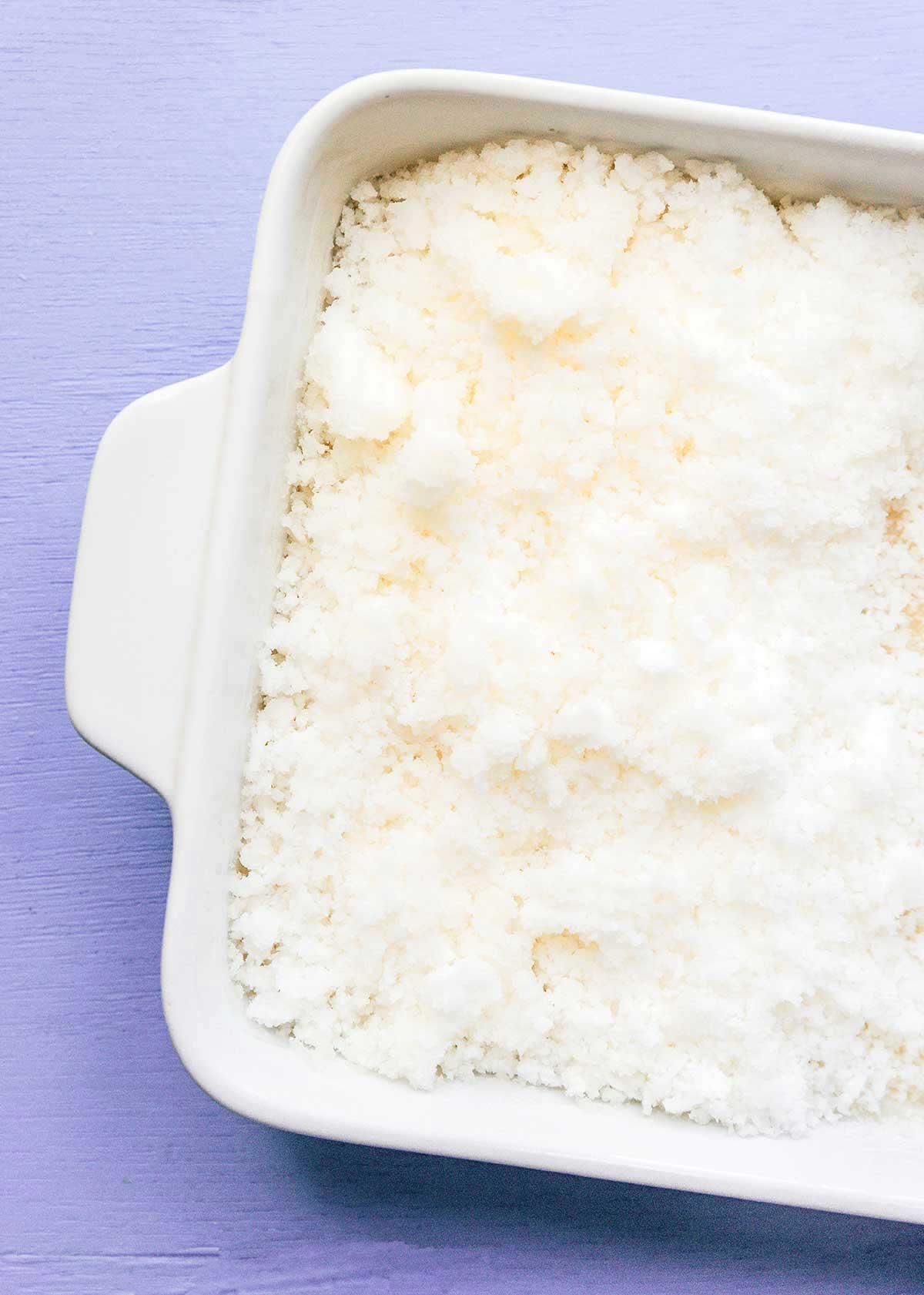 Einfache Lavendel-Zitronenlimonade (Saft oder Slush!) 8 Eine flache Auflaufform, gefüllt mit eisigem Lavendel-Zitronenlimonaden-Slush, mit sichtbaren Eiskristallen und einer Gabel zum Umrühren, steht im Gefrierschrank.