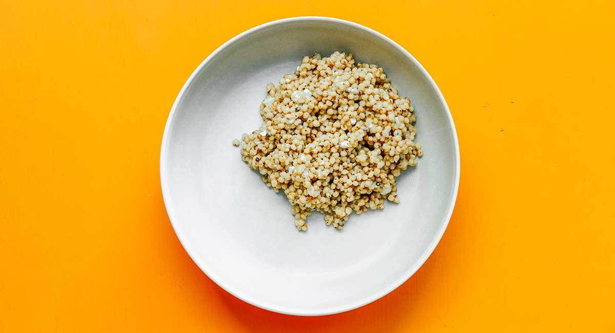 Geröstete Gemüse-Getreide-Bowls 9 Eine weiße Schüssel gefüllt mit frisch gekochtem und aufgelockertem Sorghum.
