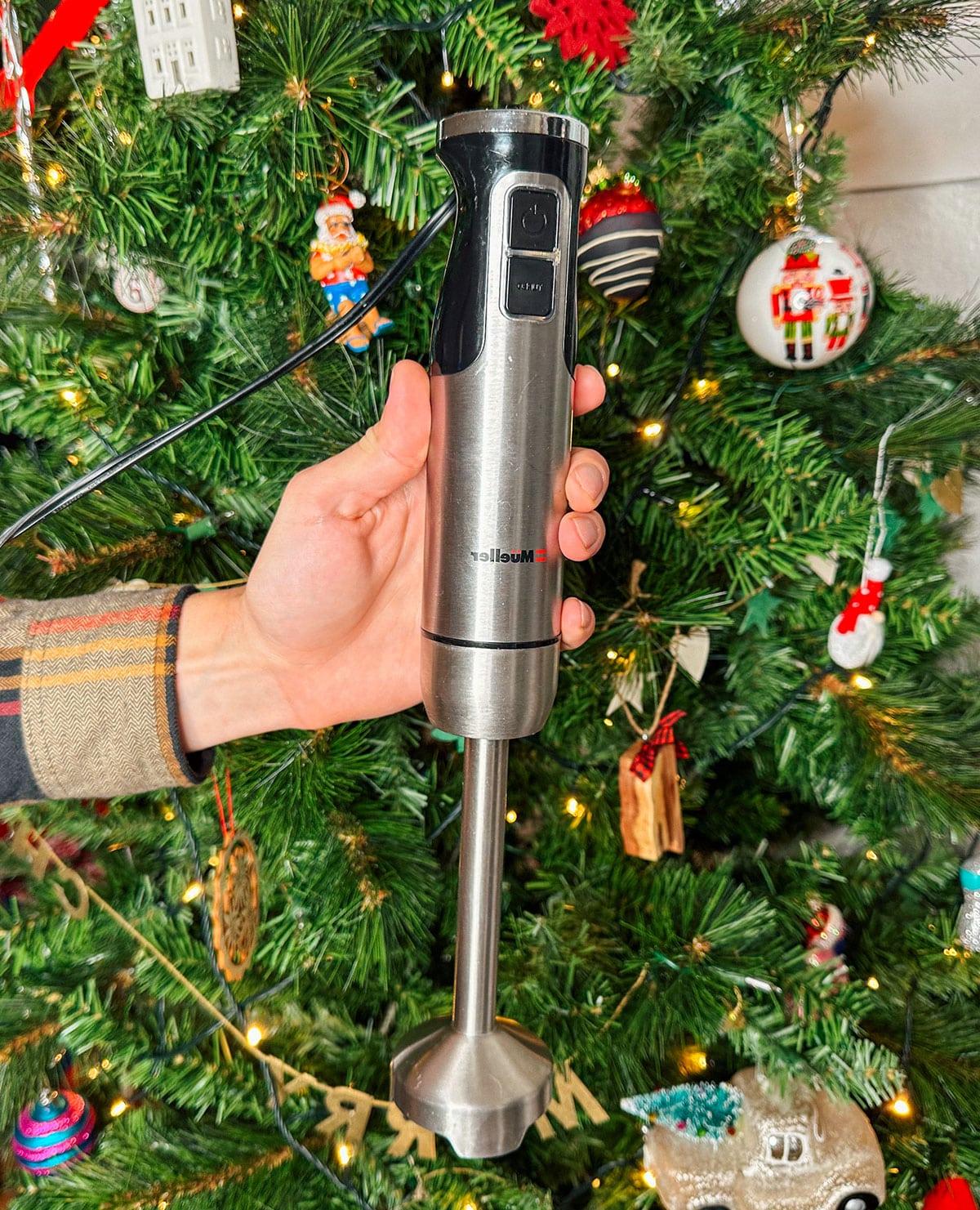 Ein praktischer Stabmixer als Geschenk vor einem Weihnachtsbaum.